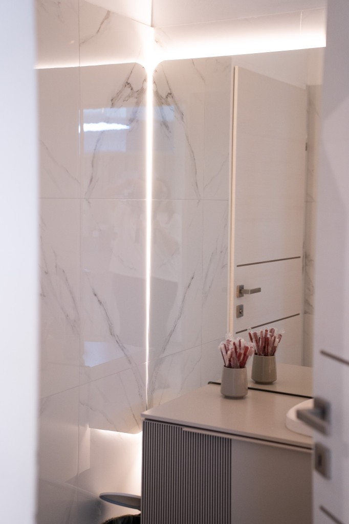Modernes WC mit Marmorfliesen und indirekter Beleuchtung